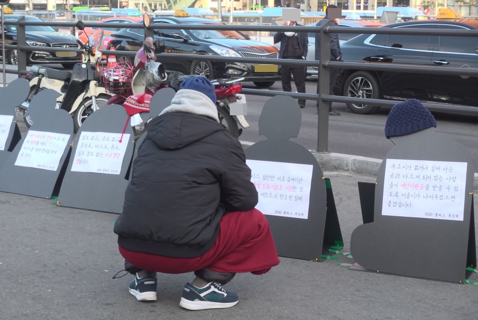 2020홈리스추모제 당시 서울역 광장에 전시된 '코로나19 상황 속에서 홈리스의 이야기'를 읽고 있는 L님 